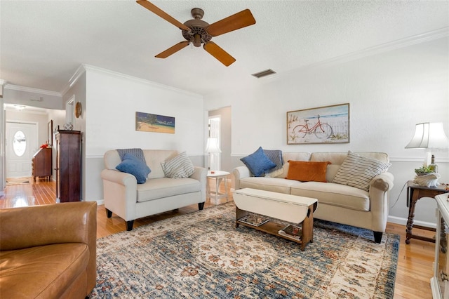 living room with hardwood / wood-style flooring, ceiling fan, crown molding, and a textured ceiling