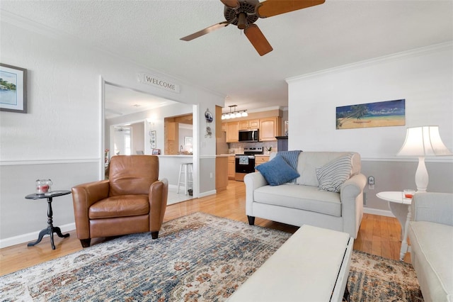 living room featuring ceiling fan, light hardwood / wood-style flooring, crown molding, and a textured ceiling