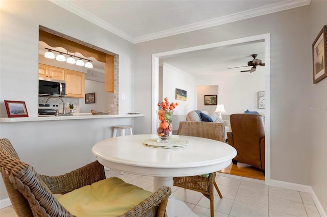 tiled dining room with ceiling fan and crown molding