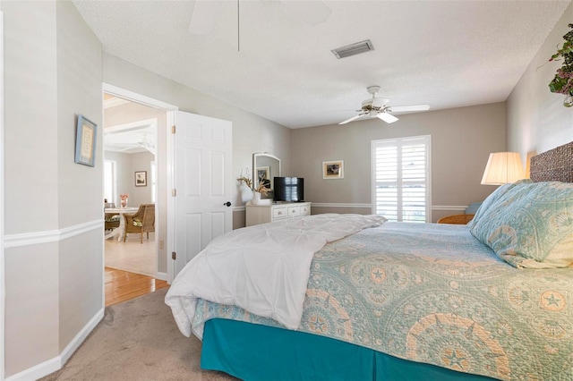 carpeted bedroom featuring ceiling fan and a textured ceiling