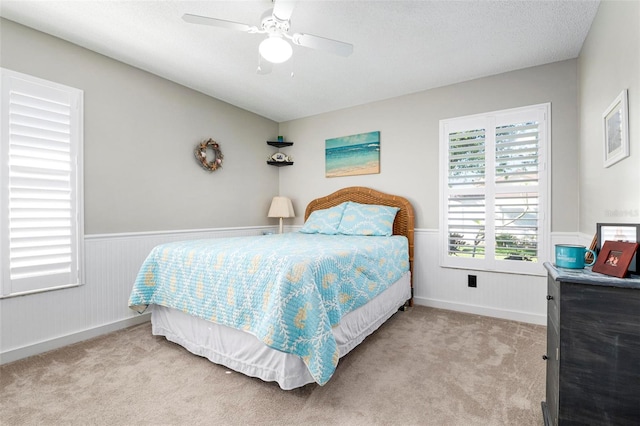 carpeted bedroom featuring ceiling fan and a textured ceiling