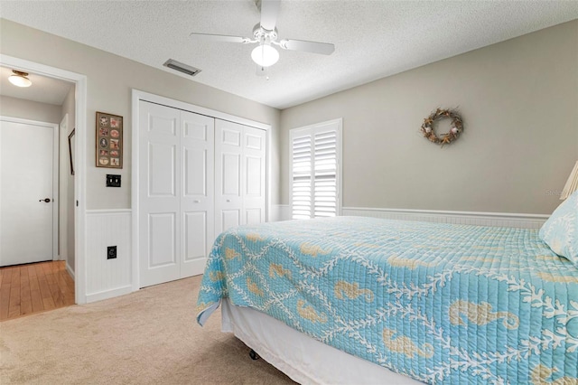 bedroom featuring ceiling fan, a closet, carpet floors, and a textured ceiling