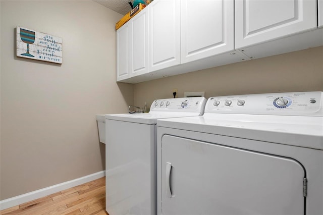 washroom with washer and clothes dryer, cabinets, and light wood-type flooring