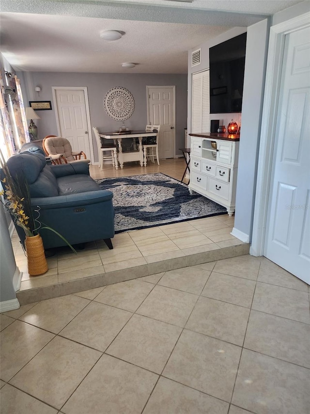 tiled living room featuring a textured ceiling