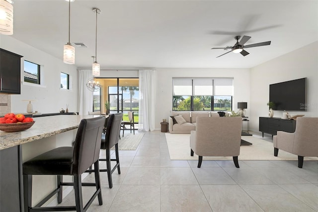 living room featuring ceiling fan with notable chandelier and light tile patterned flooring