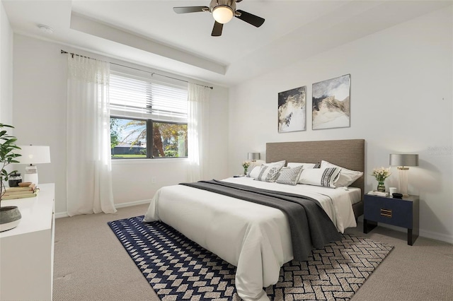 bedroom featuring light colored carpet, ceiling fan, and a tray ceiling