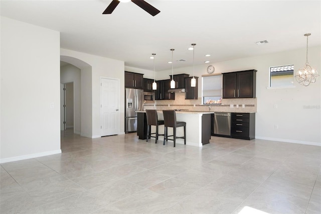 kitchen featuring appliances with stainless steel finishes, a center island, hanging light fixtures, and backsplash