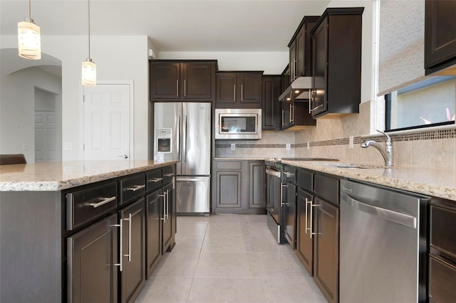 kitchen with dark brown cabinetry, ventilation hood, stainless steel appliances, sink, and hanging light fixtures