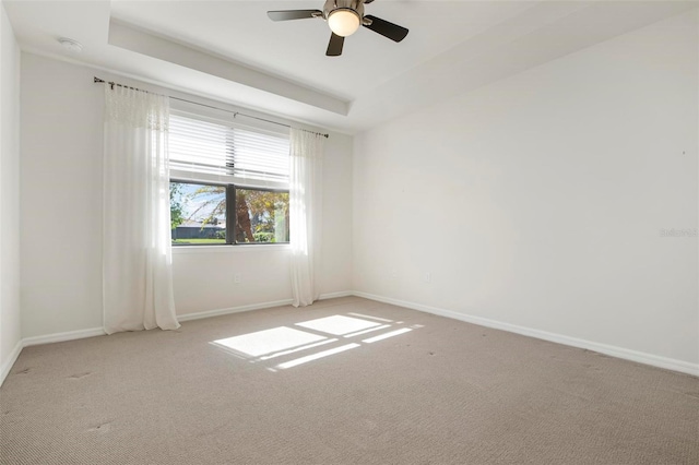 spare room with carpet flooring, a tray ceiling, and ceiling fan