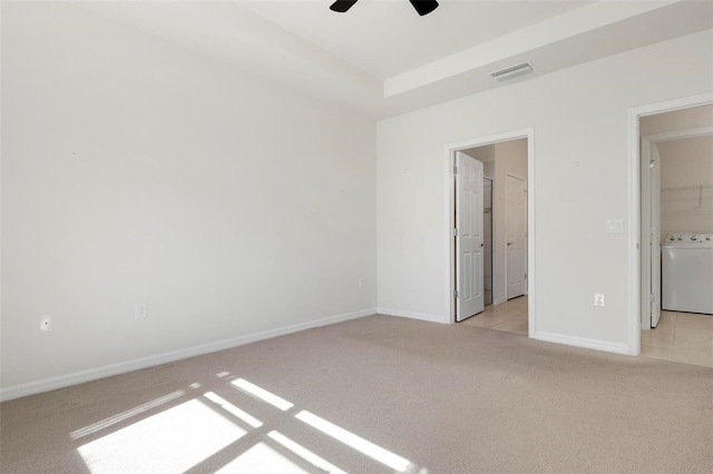 unfurnished bedroom with ceiling fan, washer / clothes dryer, light carpet, and connected bathroom