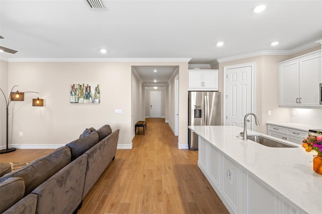 kitchen featuring light stone countertops, stainless steel refrigerator with ice dispenser, white cabinets, and sink