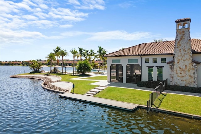 back of house featuring a lawn and a water view