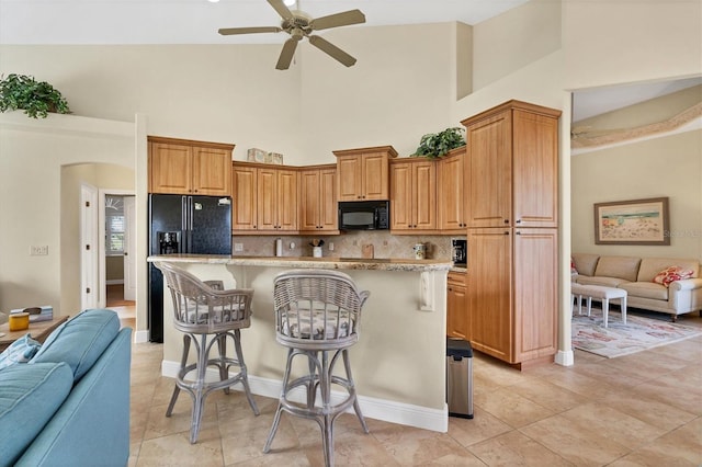 kitchen with black appliances, a breakfast bar, a center island, and high vaulted ceiling