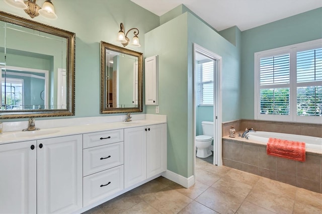 bathroom with tile patterned floors, vanity, tiled bath, and toilet