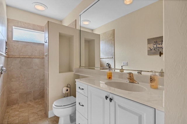 bathroom with vanity, toilet, and a tile shower