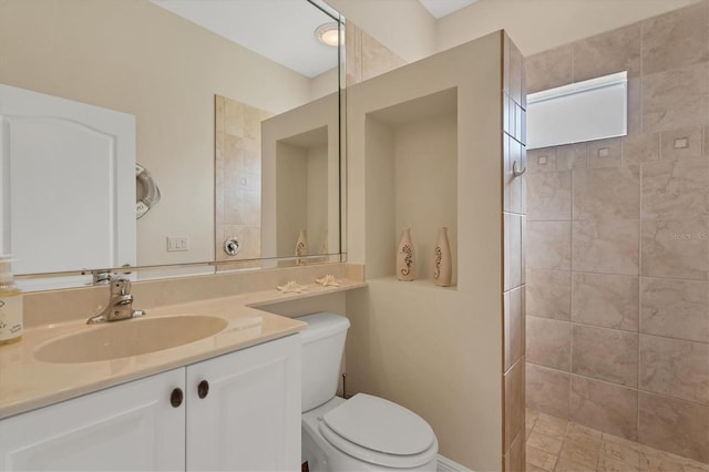 bathroom featuring vanity, toilet, and tiled shower