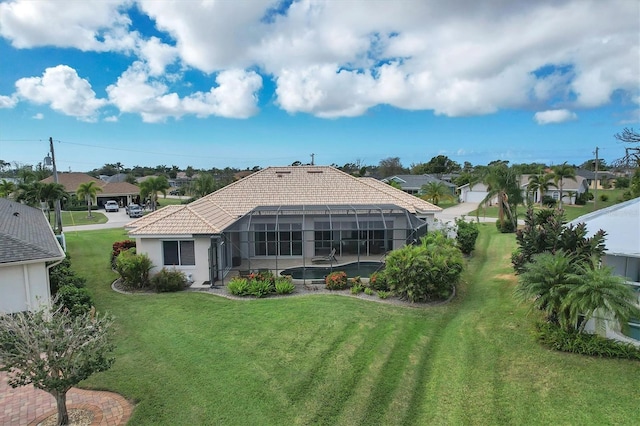 rear view of property with glass enclosure and a yard