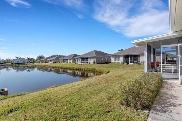 view of yard featuring a sunroom and a water view