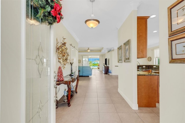 hall featuring light tile patterned floors, crown molding, and sink