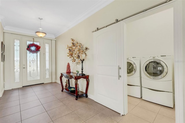 entryway with a barn door, washing machine and dryer, ornamental molding, and light tile patterned floors