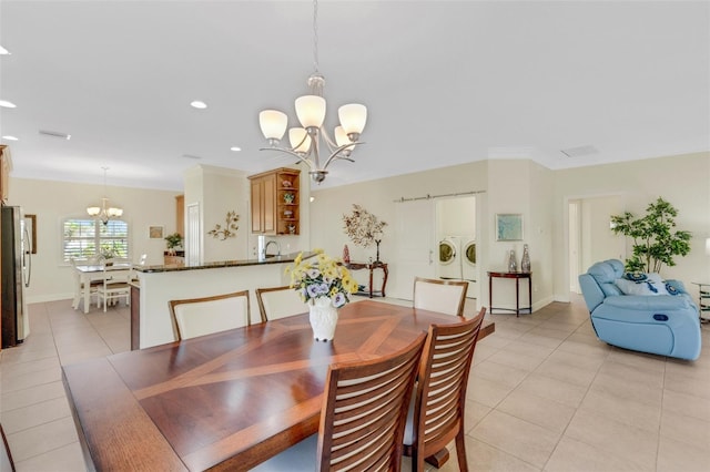 tiled dining area with a chandelier, washer and dryer, and sink