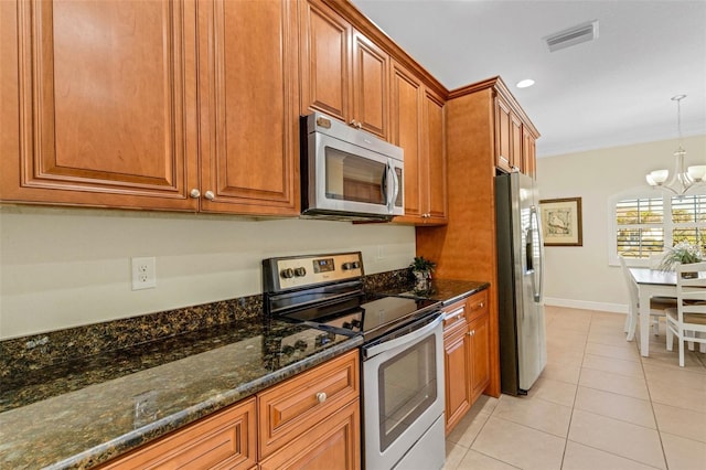 kitchen with stainless steel appliances, dark stone countertops, a chandelier, hanging light fixtures, and light tile patterned flooring