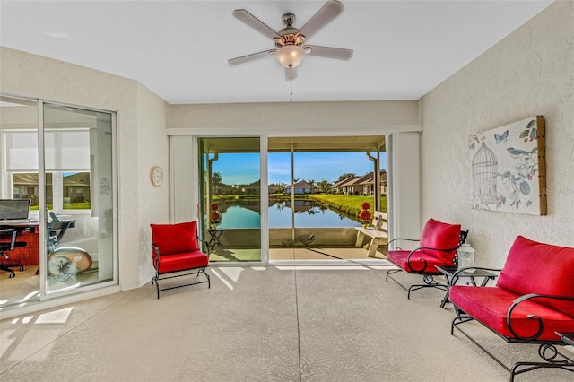 living area with ceiling fan and a water view