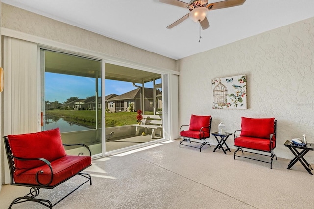 living area featuring ceiling fan and a water view