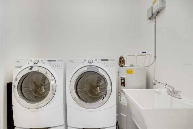 washroom featuring washing machine and clothes dryer, electric water heater, and sink