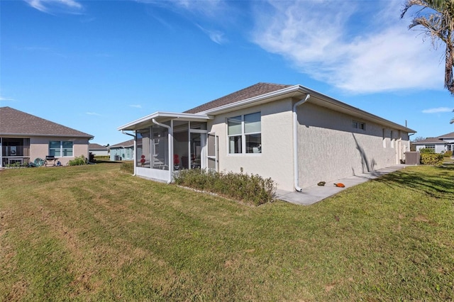 rear view of property with central air condition unit, a sunroom, and a yard