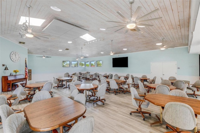 dining space with wood ceiling, ceiling fan, light hardwood / wood-style floors, and lofted ceiling with skylight