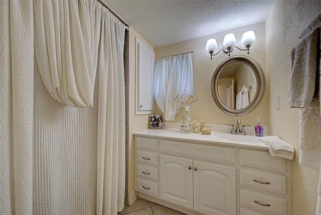 bathroom with tile patterned flooring, vanity, and a textured ceiling