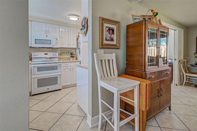 kitchen featuring light tile patterned floors, white cabinets, and white appliances