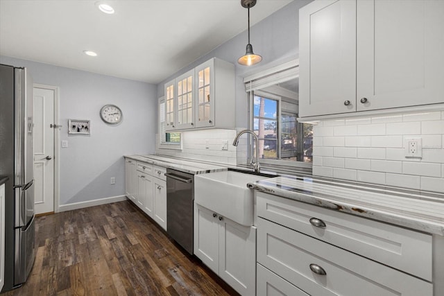 kitchen featuring appliances with stainless steel finishes, tasteful backsplash, light stone counters, dark hardwood / wood-style floors, and white cabinetry