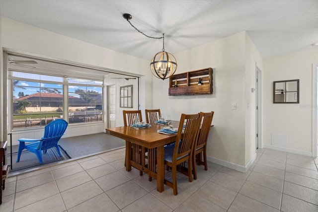 tiled dining area with ceiling fan with notable chandelier