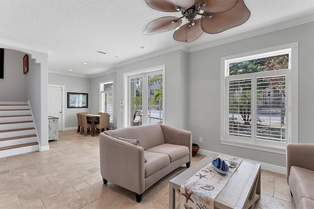 living room with plenty of natural light, ceiling fan, ornamental molding, and a textured ceiling