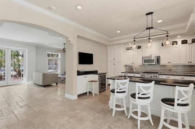 kitchen with a kitchen bar, tasteful backsplash, white cabinets, and sink