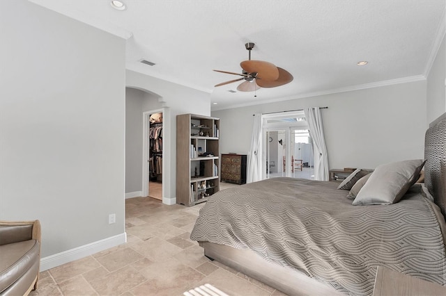 bedroom with a spacious closet, a closet, ceiling fan, and ornamental molding