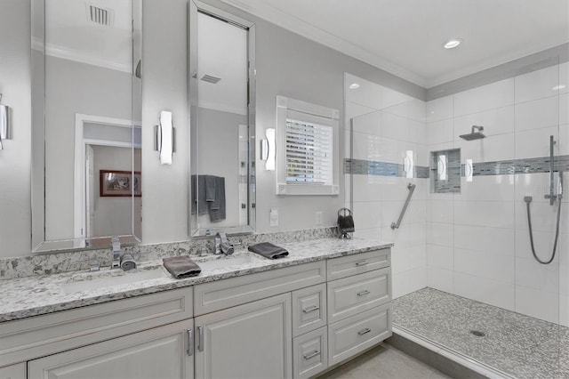 bathroom with vanity, a tile shower, and crown molding