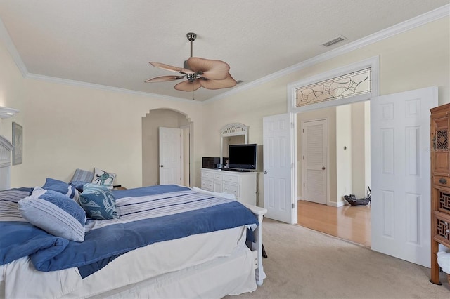 carpeted bedroom featuring ceiling fan, crown molding, and a textured ceiling