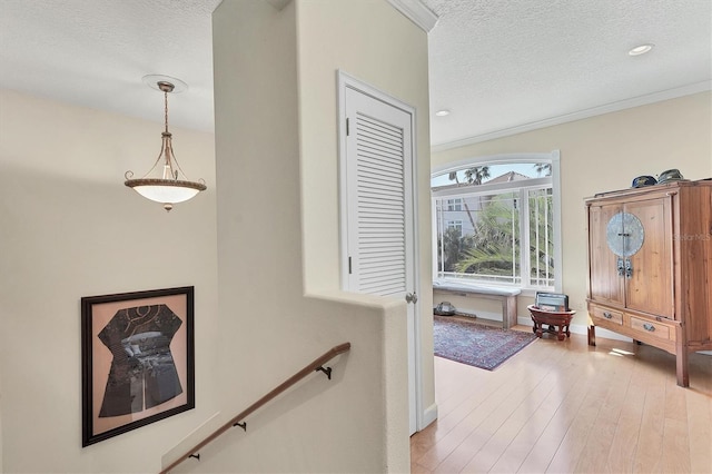 hall with a textured ceiling, hardwood / wood-style flooring, and ornamental molding