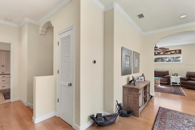 hall with light wood-type flooring and ornamental molding