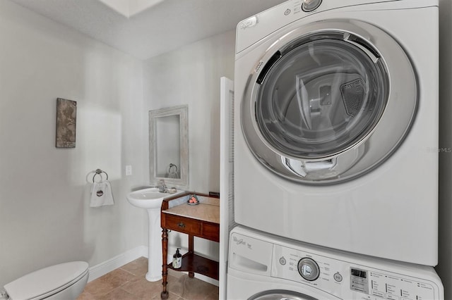 laundry room featuring light tile patterned floors and stacked washer and dryer