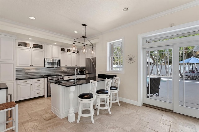 kitchen featuring white cabinets, ornamental molding, tasteful backsplash, decorative light fixtures, and stainless steel appliances