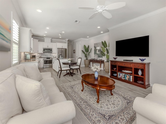 living room featuring ceiling fan, light wood-type flooring, and ornamental molding