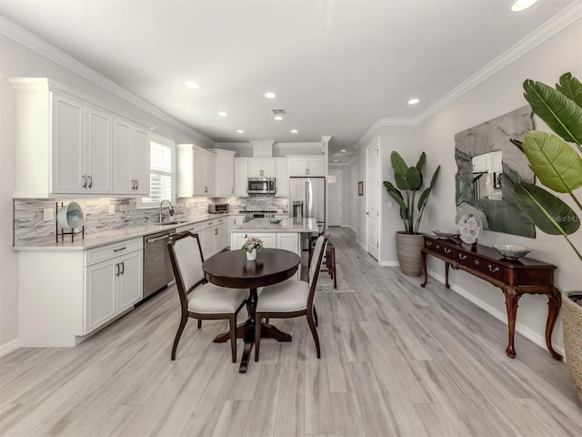 dining area featuring light hardwood / wood-style floors, crown molding, and sink