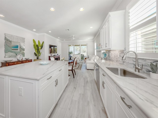 kitchen with light stone counters, white cabinetry, sink, and tasteful backsplash