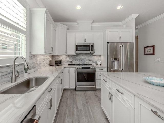 kitchen with light stone counters, sink, white cabinets, and appliances with stainless steel finishes