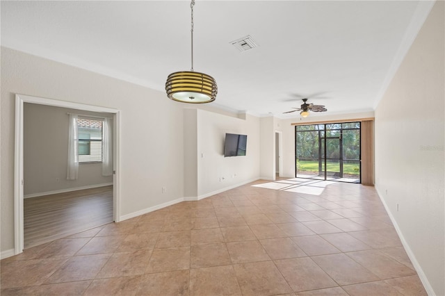 unfurnished room featuring ceiling fan, crown molding, and light tile patterned floors