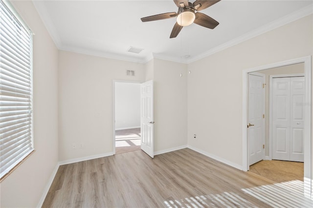 unfurnished bedroom with ceiling fan, light wood-type flooring, crown molding, and multiple windows